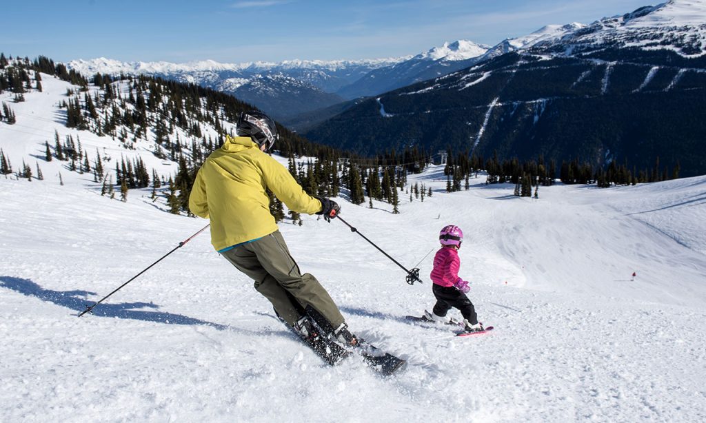 uomo che scia nella neve insieme a bambino
